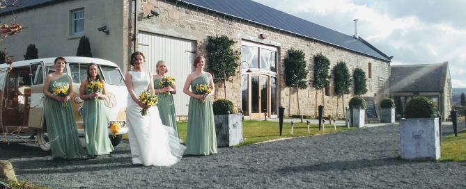 Sunny photo of bride and bridesmaids outside of Healey Barn