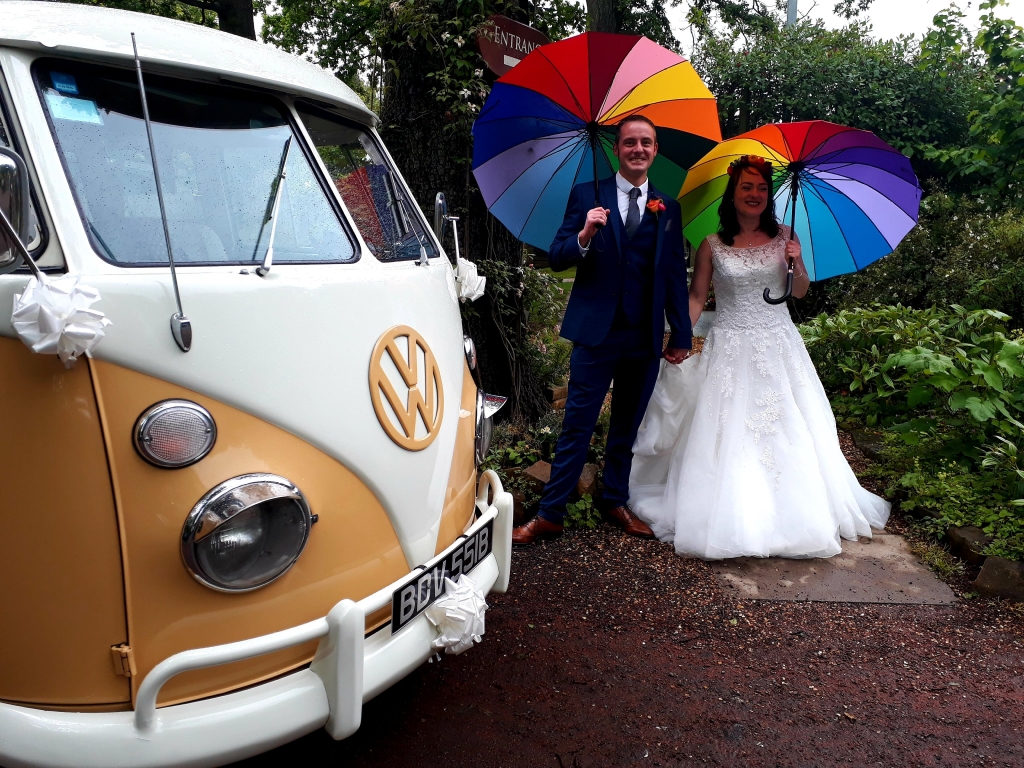 Campervan outside the Parlour at Blagdon entrance, bride and groom holding colourful Umbrella's