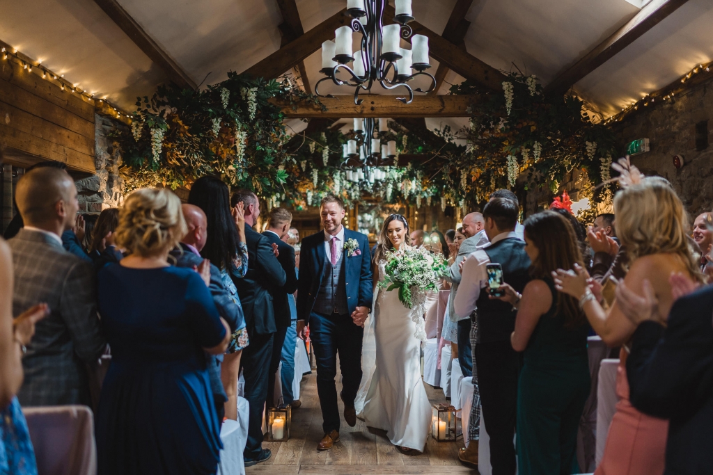 Newly married couple walk back up the Aisle at The South Causey with family watching