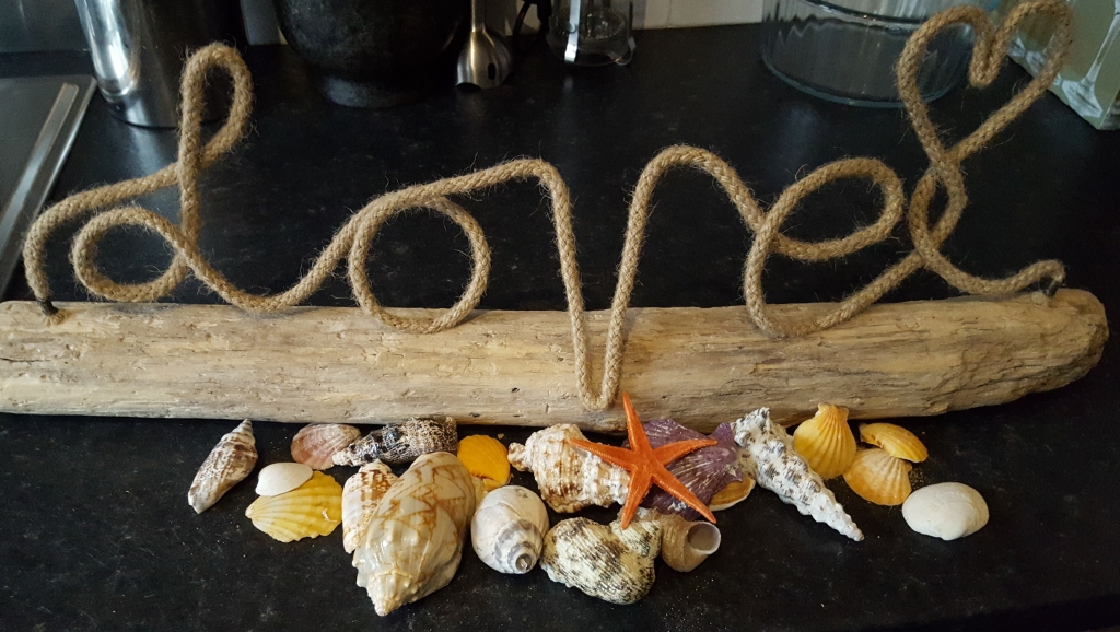 Hand made artisan wood and rope love sign with a selection of sea shells