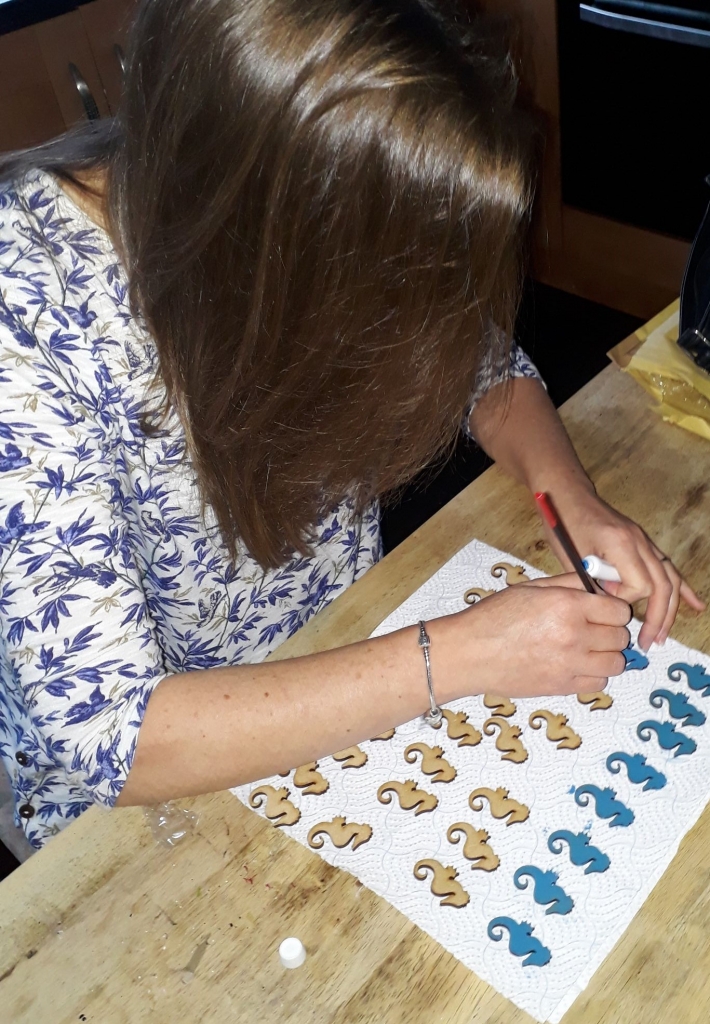 Hand painting wooden seahorses with blue paint