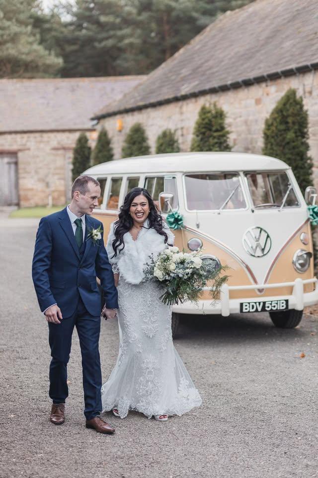Smiling Bride with her Groom outside of Healey Barn with a Volkswagen Wedding Camper